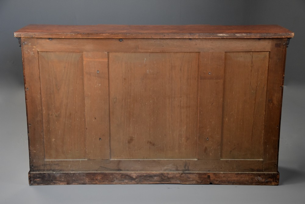 A mid-19th century mahogany breakfront low bookcase featuring pointed Gothic arch details, flanked by two panelled cupboard doors and an open central shelving area. View XIII