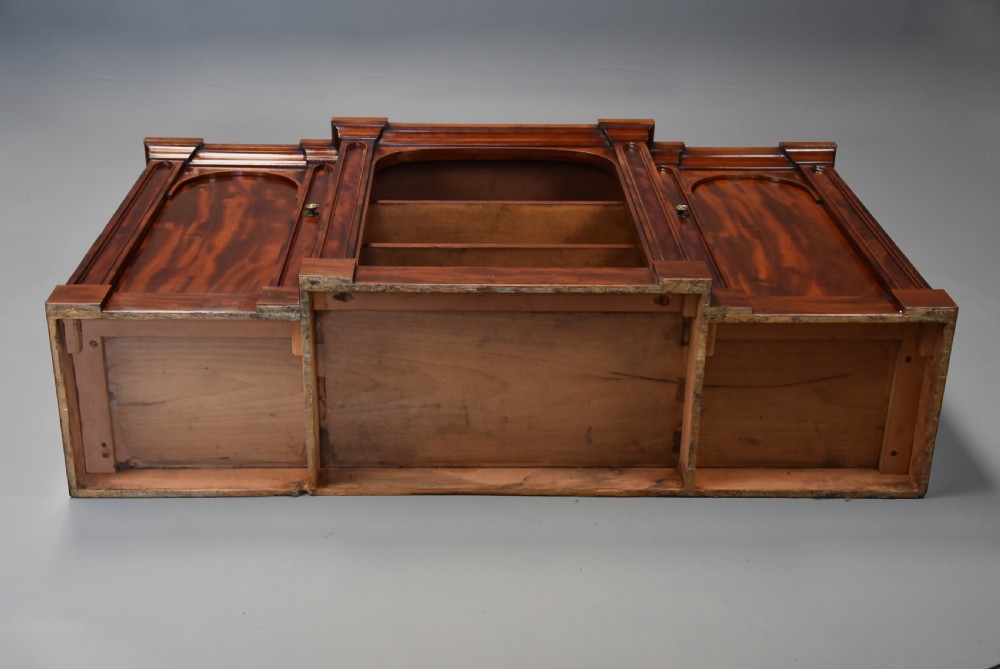 A mid-19th century mahogany breakfront low bookcase featuring pointed Gothic arch details, flanked by two panelled cupboard doors and an open central shelving area. View XIV