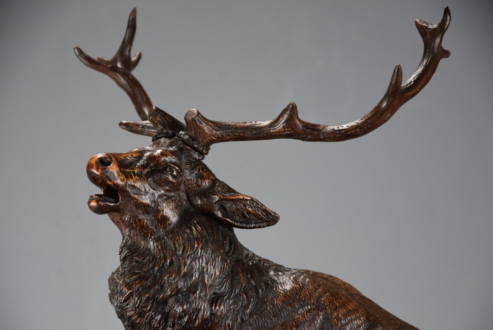 A late 19th-century dark carved linden wood sculpture depicting a roaring stag standing above a doe and lying fawn on a naturalistic base. View XI