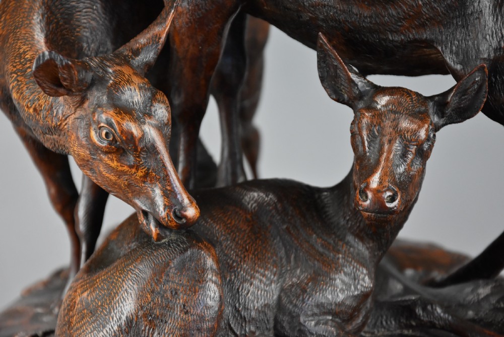A late 19th-century dark carved linden wood sculpture depicting a roaring stag standing above a doe and lying fawn on a naturalistic base. View XII