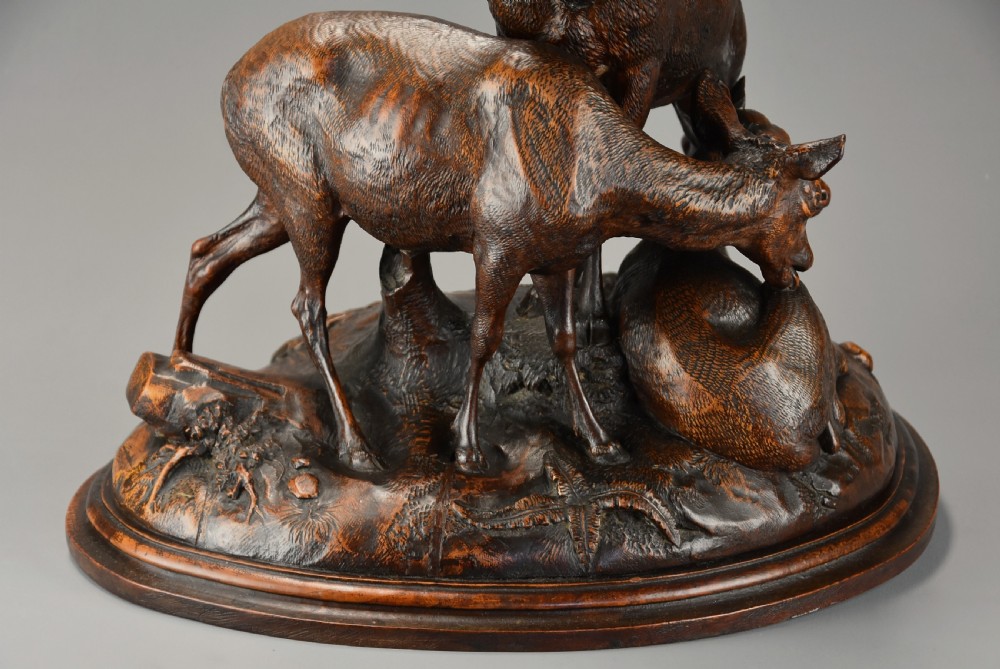 A late 19th-century dark carved linden wood sculpture depicting a roaring stag standing above a doe and lying fawn on a naturalistic base. View XIV