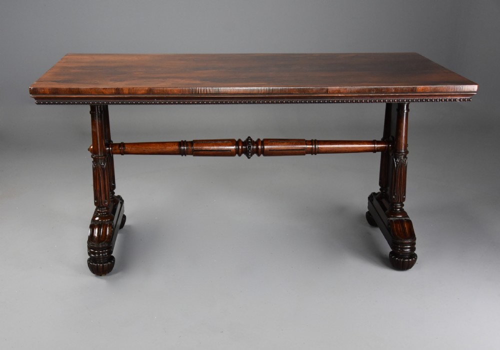 A William IV rosewood centre writing table featuring a rectangular top, beaded border, carved end supports, a central turned stretcher, and lobed feet. View II