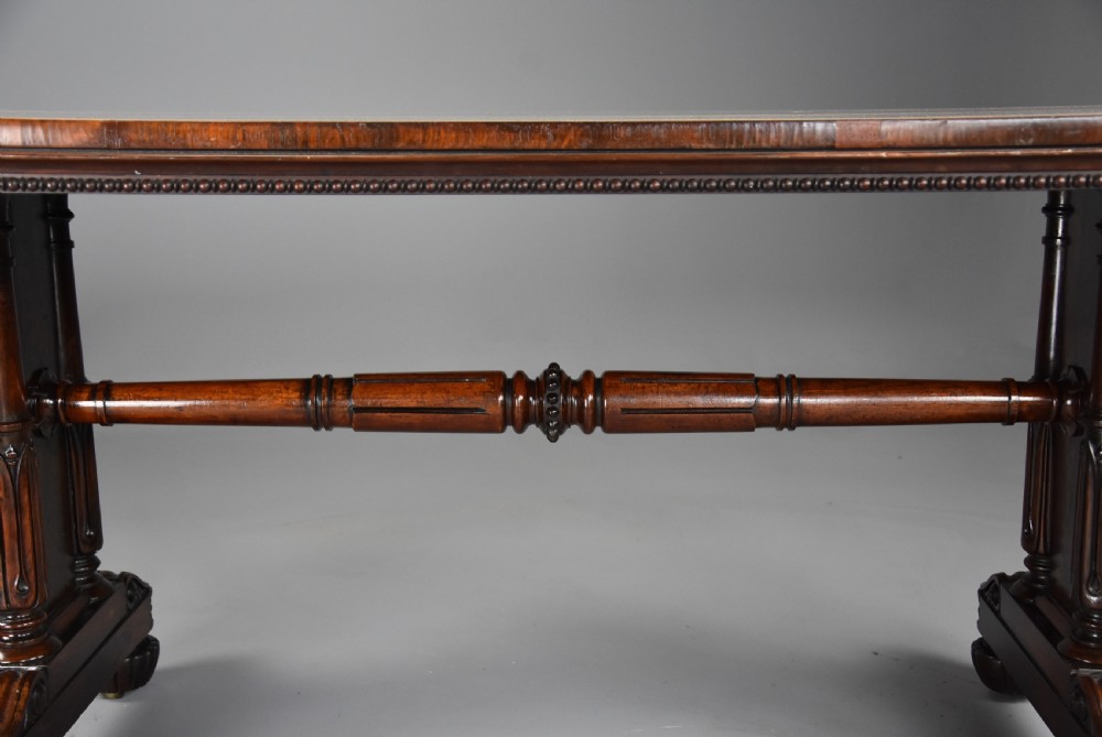 A William IV rosewood centre writing table featuring a rectangular top, beaded border, carved end supports, a central turned stretcher, and lobed feet. View IX