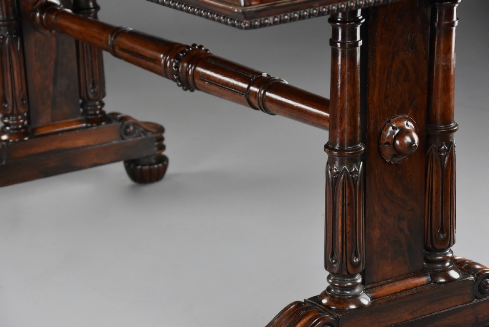 A William IV rosewood centre writing table featuring a rectangular top, beaded border, carved end supports, a central turned stretcher, and lobed feet. View XI