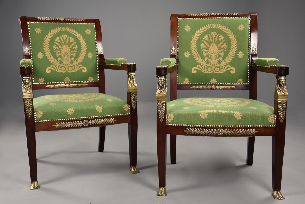 Pair of late 19th-century French Empire style mahogany open armchairs upholstered in green patterned fabric with brass mounts and paw feet.