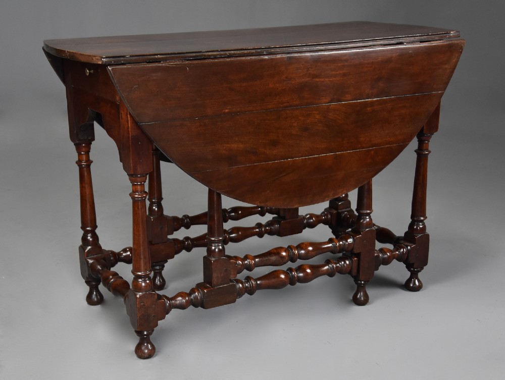 An 18th-century dark walnut gateleg table with folding drop leaves, turned supports, and lower stretchers. View II