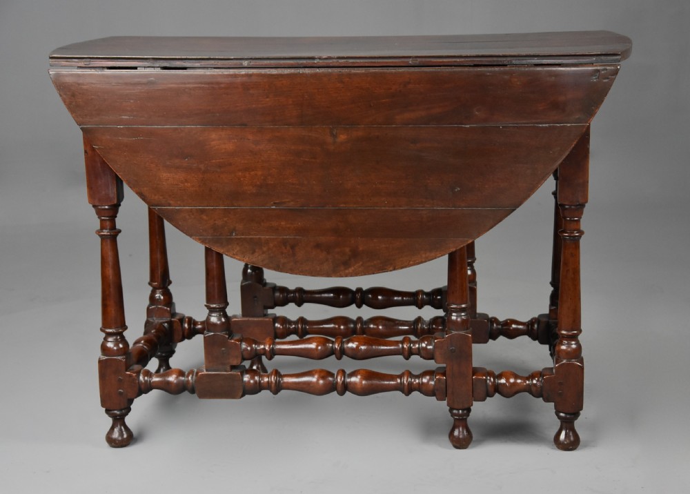 An 18th-century dark walnut gateleg table with folding drop leaves, turned supports, and lower stretchers. View IV