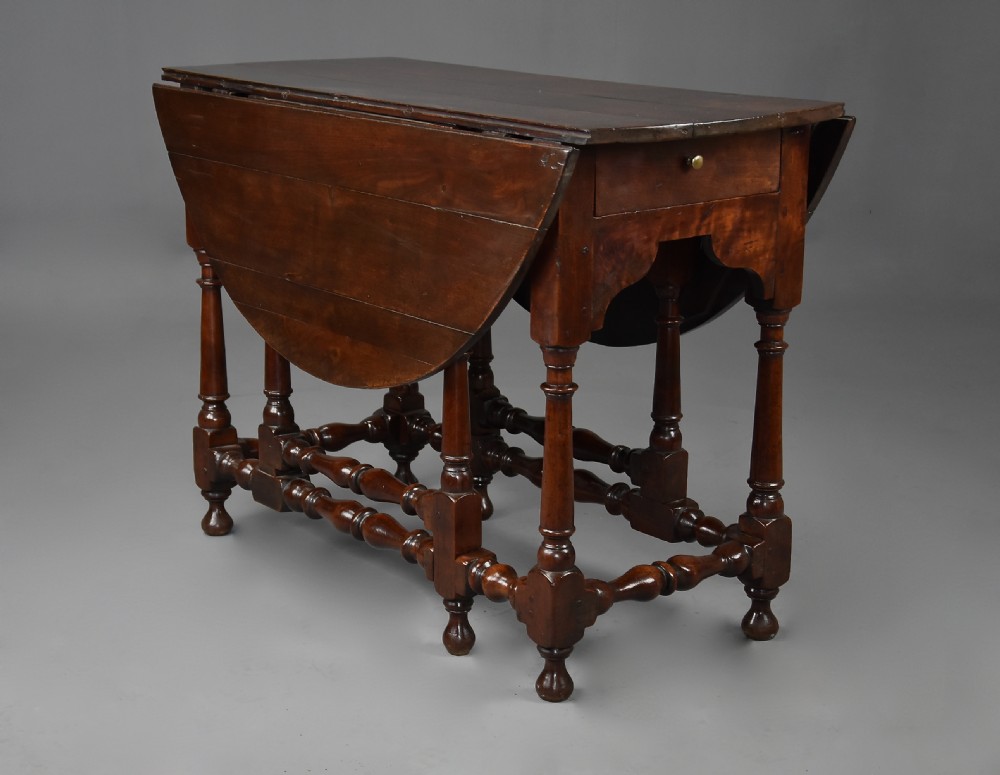 An 18th-century dark walnut gateleg table with folding drop leaves, turned supports, and lower stretchers. View V