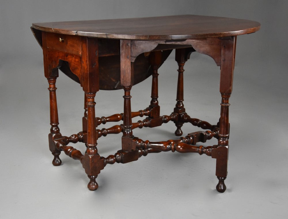 An 18th-century dark walnut gateleg table with folding drop leaves, turned supports, and lower stretchers. View IX