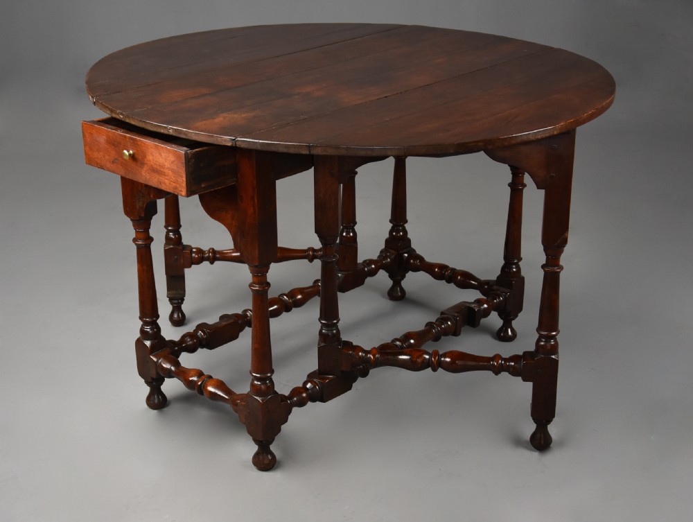 An 18th-century dark walnut gateleg table with folding drop leaves, turned supports, and lower stretchers. View XI