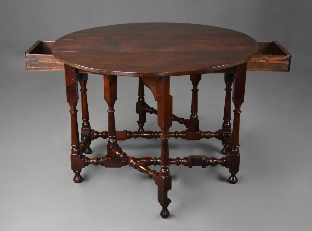 An 18th-century dark walnut gateleg table with folding drop leaves, turned supports, and lower stretchers. View XII