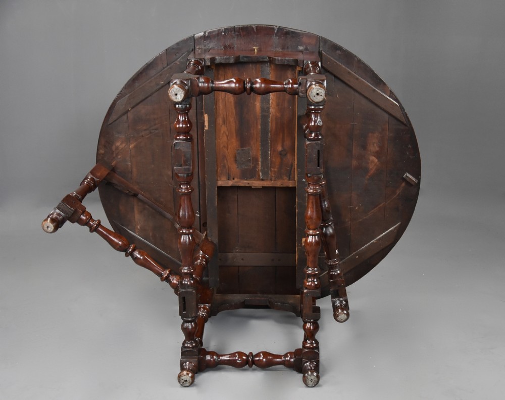 An 18th-century dark walnut gateleg table with folding drop leaves, turned supports, and lower stretchers. View XVI