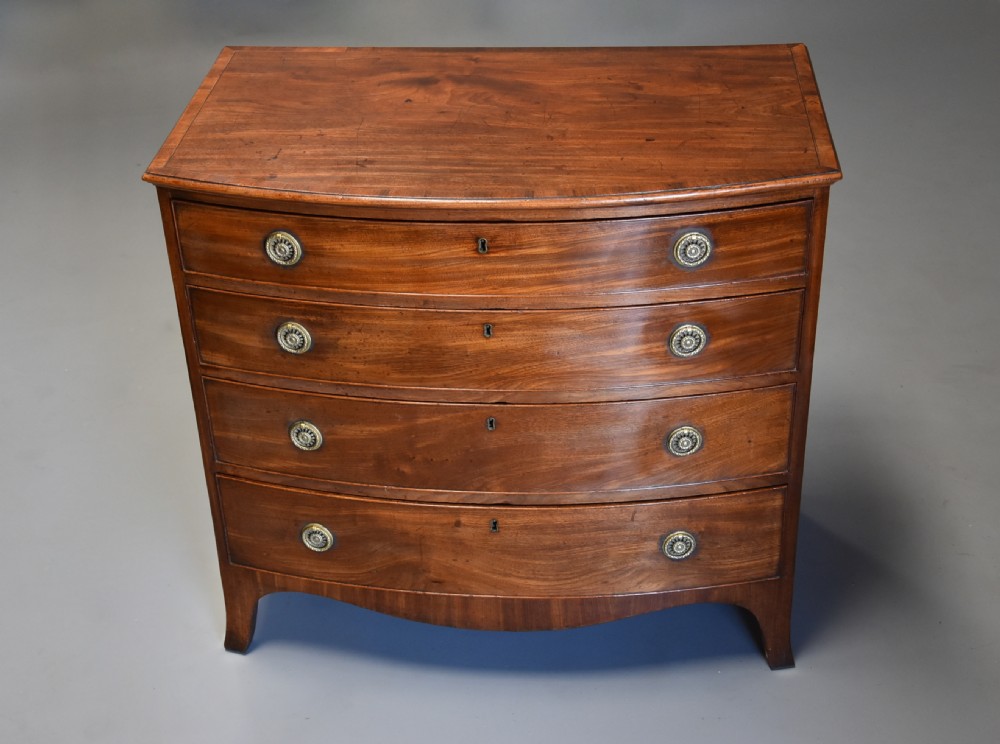 A late eighteenth-century mahogany bow-front chest of drawers featuring four graduated drawers with circular brass handles and splayed bracket feet. View II