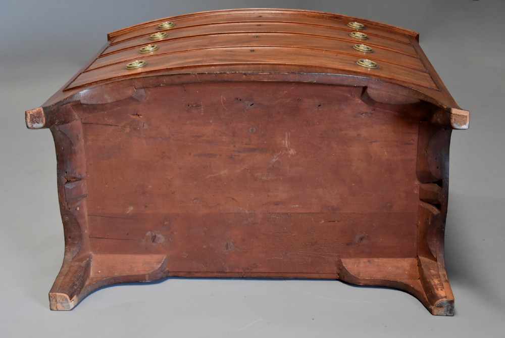A late eighteenth-century mahogany bow-front chest of drawers featuring four graduated drawers with circular brass handles and splayed bracket feet. View XI