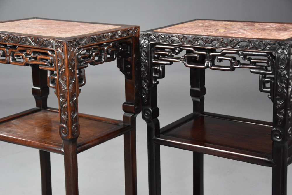 A matched pair of late nineteenth-century Chinese dark hardwood plant stands featuring inset marble tops, carved openwork aprons, and two lower tiers. View VI