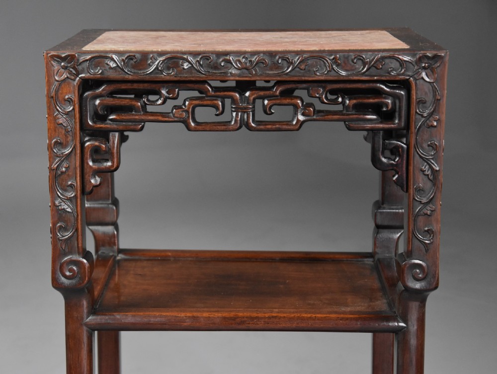A matched pair of late nineteenth-century Chinese dark hardwood plant stands featuring inset marble tops, carved openwork aprons, and two lower tiers. View VII