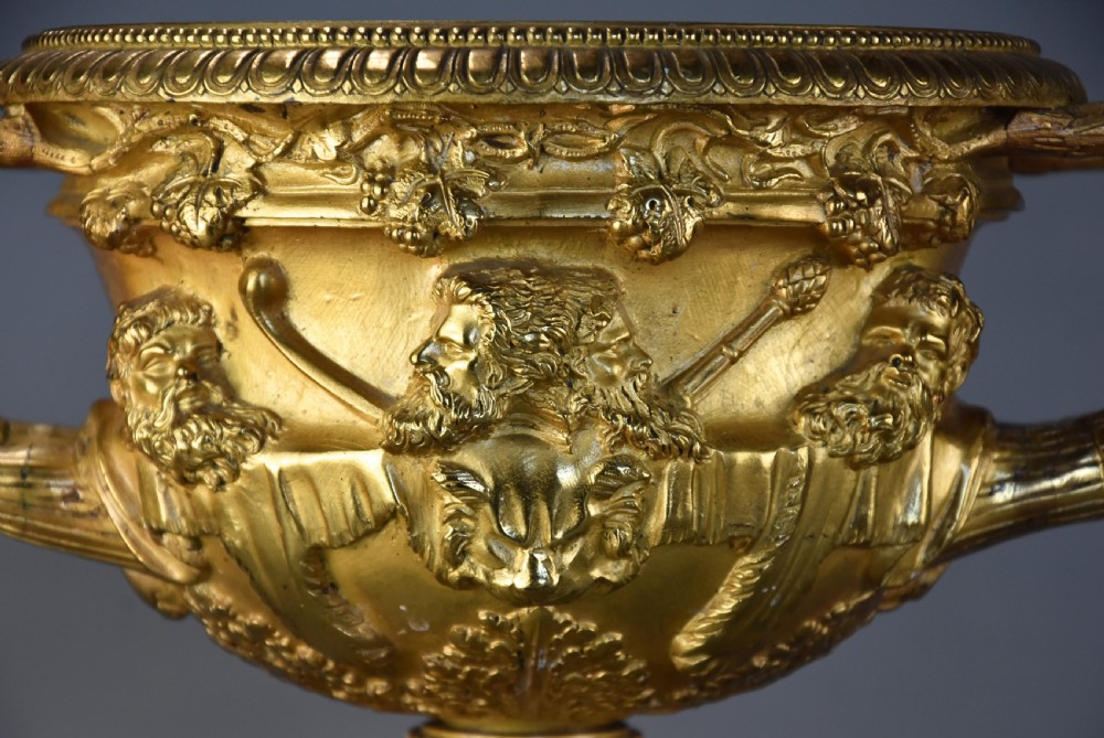 A 19th-century gilt bronze reduction of the Warwick Vase featuring high-relief Bacchic masks, intertwined vine handles, and a pedestal base. View V