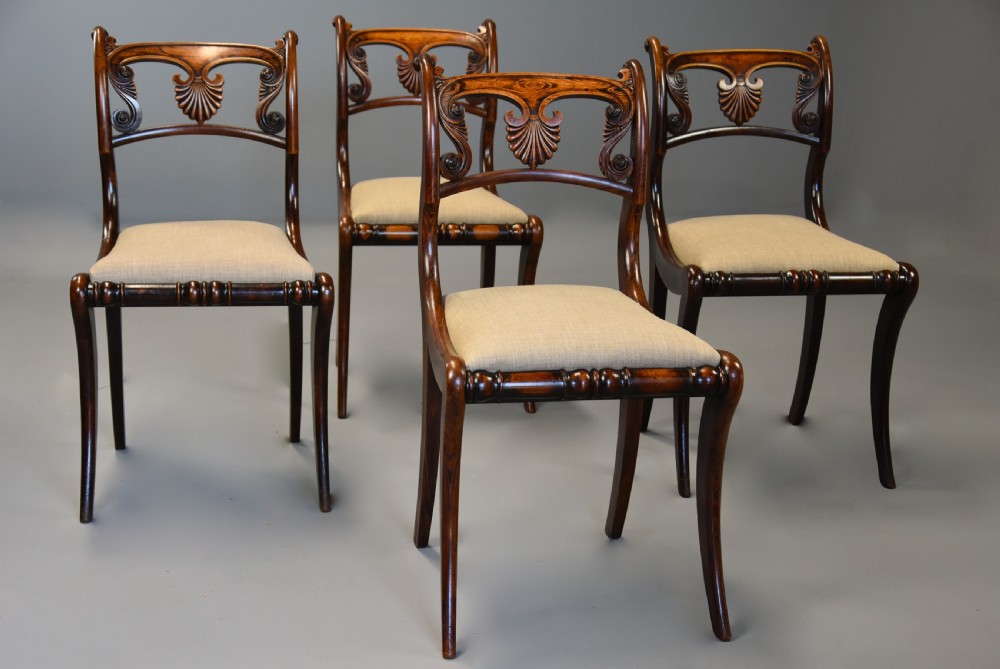 A set of thirteen early nineteenth-century Regency dining chairs featuring carved anthemion backrests, curved legs, and light neutral upholstered seat cushions. View XI
