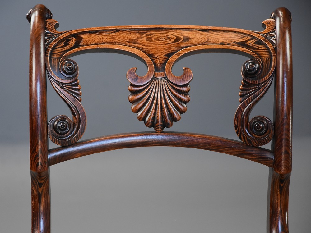 A set of thirteen early nineteenth-century Regency dining chairs featuring carved anthemion backrests, curved legs, and light neutral upholstered seat cushions. View XIV