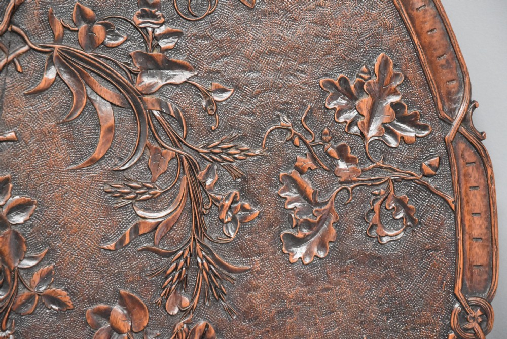 A circular late 19th-century dark brown linden wood centre table featuring intricate foliate carvings on the top, a decorated pedestal, and a tripod base. View XI