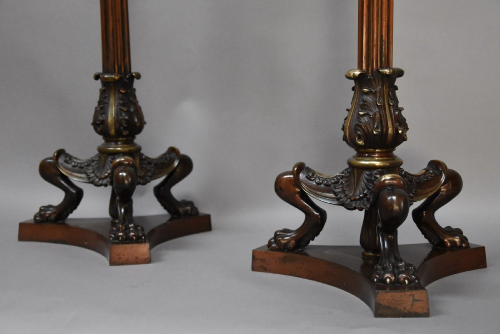 A pair of tall late 19th-century Regency style mahogany torcheres featuring fluted columns, ornate bronze monopodia legs, and triform bases. View V