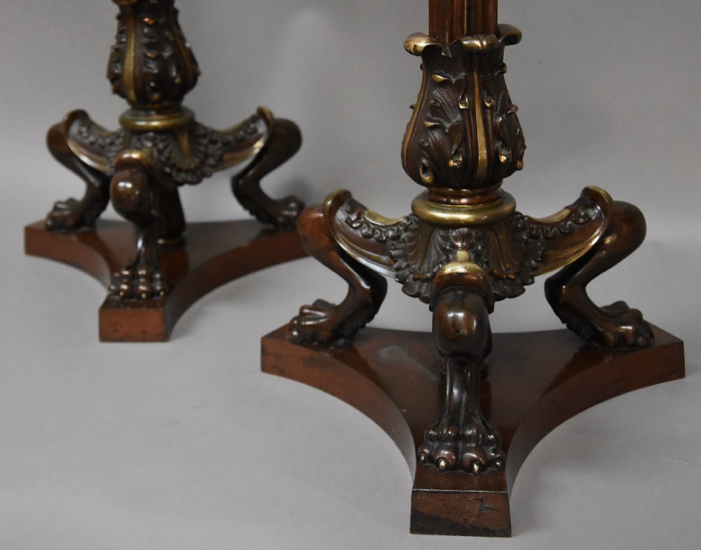 A pair of tall late 19th-century Regency style mahogany torcheres featuring fluted columns, ornate bronze monopodia legs, and triform bases. View VI