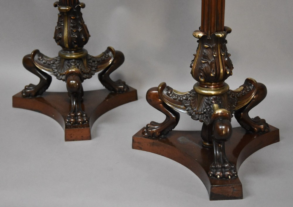 A pair of tall late 19th-century Regency style mahogany torcheres featuring fluted columns, ornate bronze monopodia legs, and triform bases. View X