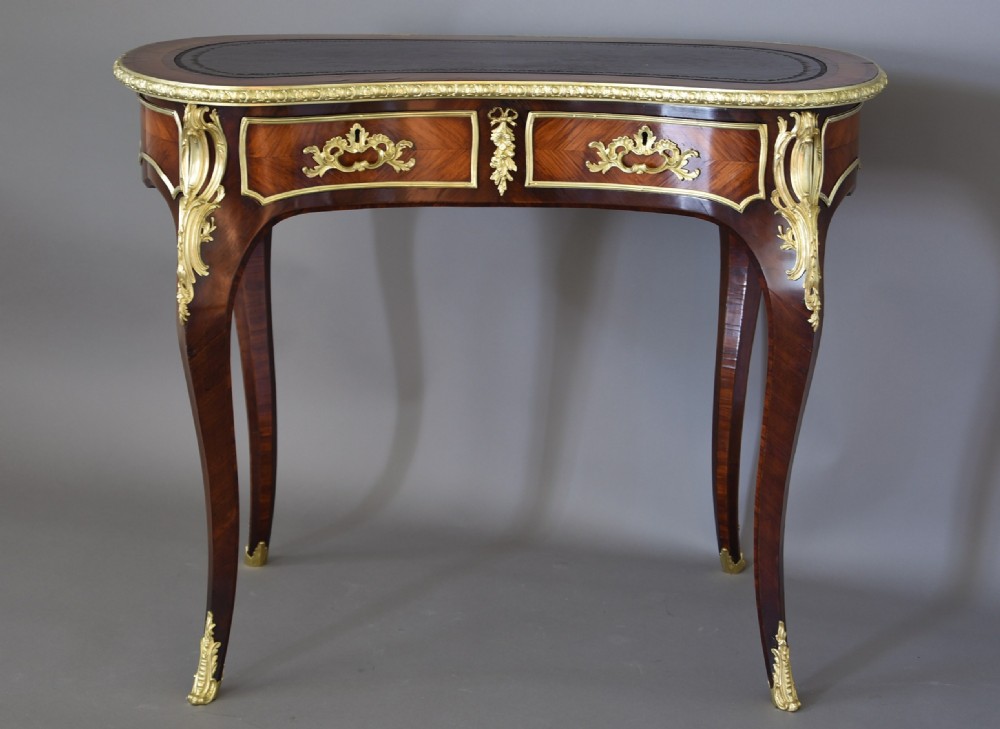 A 19th-century kidney-shaped kingwood writing desk featuring gilt-bronze ormolu mounts, a leather top, and curved cabriole legs. View V