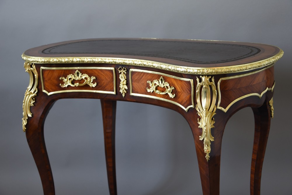 A 19th-century kidney-shaped kingwood writing desk featuring gilt-bronze ormolu mounts, a leather top, and curved cabriole legs. View VII