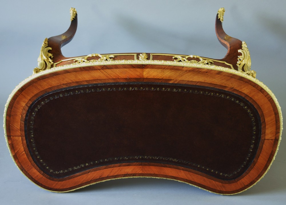 A 19th-century kidney-shaped kingwood writing desk featuring gilt-bronze ormolu mounts, a leather top, and curved cabriole legs. View X