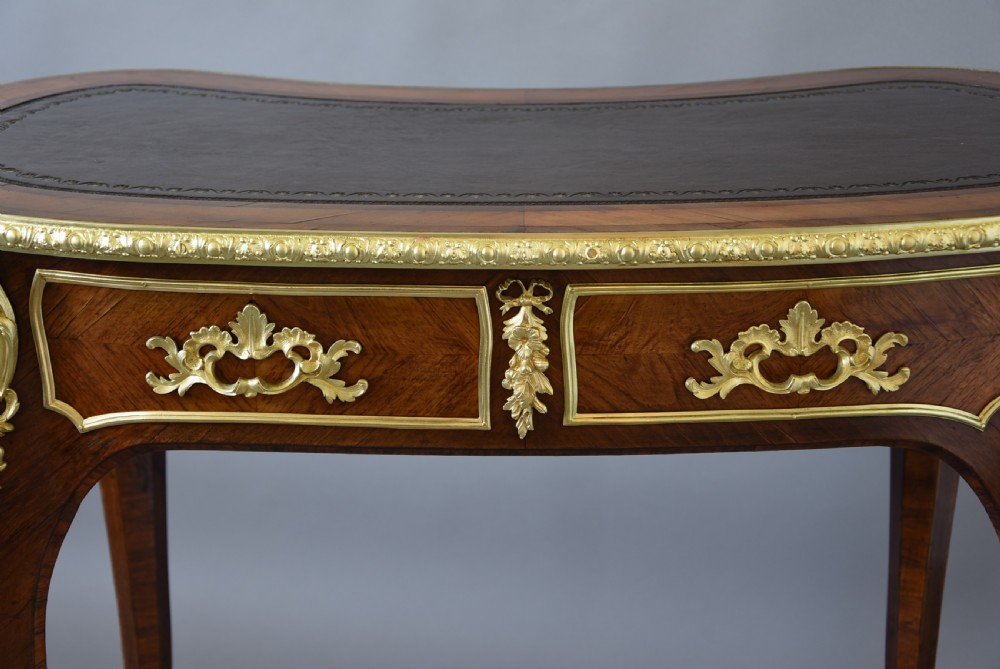 A 19th-century kidney-shaped kingwood writing desk featuring gilt-bronze ormolu mounts, a leather top, and curved cabriole legs. View XII