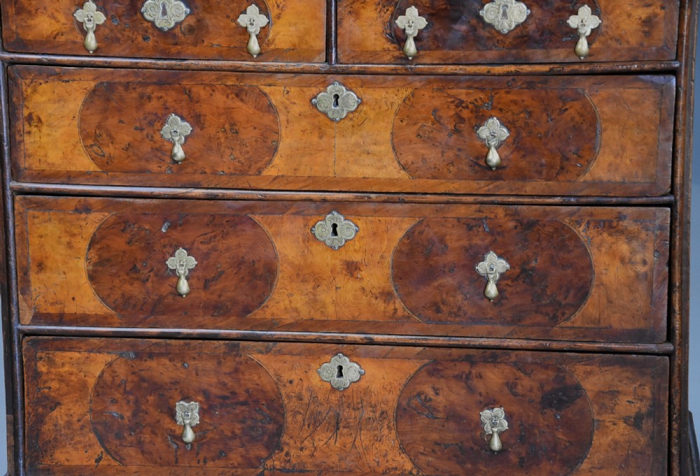 A late 17th-century William and Mary chest of drawers with oval yew wood veneers, brass teardrop handles, and dark turned bun feet. View VIII