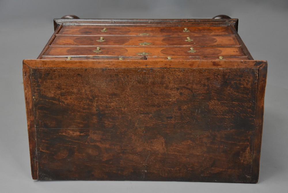A late 17th-century William and Mary chest of drawers with oval yew wood veneers, brass teardrop handles, and dark turned bun feet. View XIV