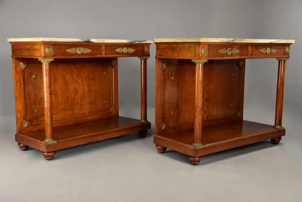 A pair of 19th-century French Empire style mahogany console tables featuring light marble tops, gilt bronze mounts, and cylindrical front columns. View II