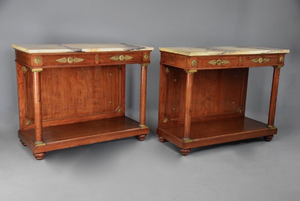 A pair of 19th-century French Empire style mahogany console tables featuring light marble tops, gilt bronze mounts, and cylindrical front columns. View III
