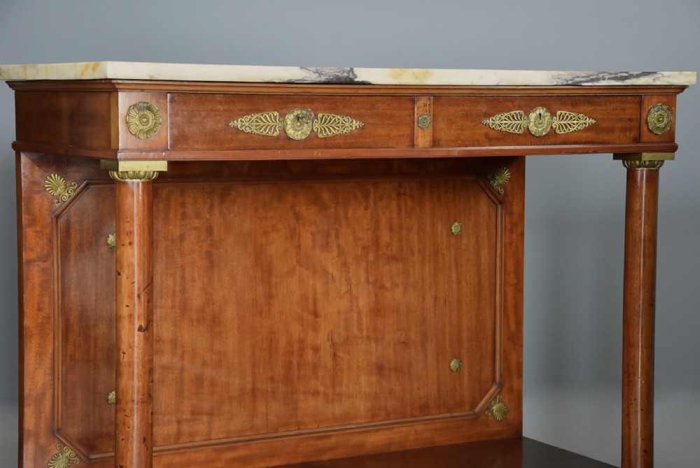 A pair of 19th-century French Empire style mahogany console tables featuring light marble tops, gilt bronze mounts, and cylindrical front columns. View VIII