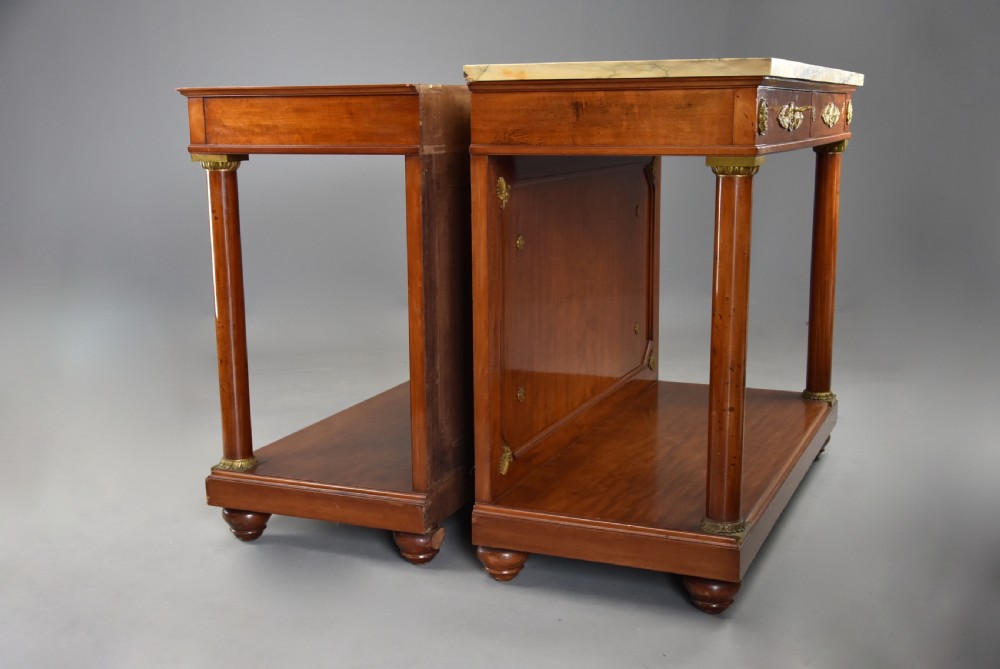 A pair of 19th-century French Empire style mahogany console tables featuring light marble tops, gilt bronze mounts, and cylindrical front columns. View XIII