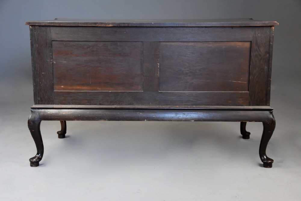 A late nineteenth-century dark flame mahogany serpentine chest of drawers featuring three graduated drawers with decorative brass handles and a carved lower apron. View XVII