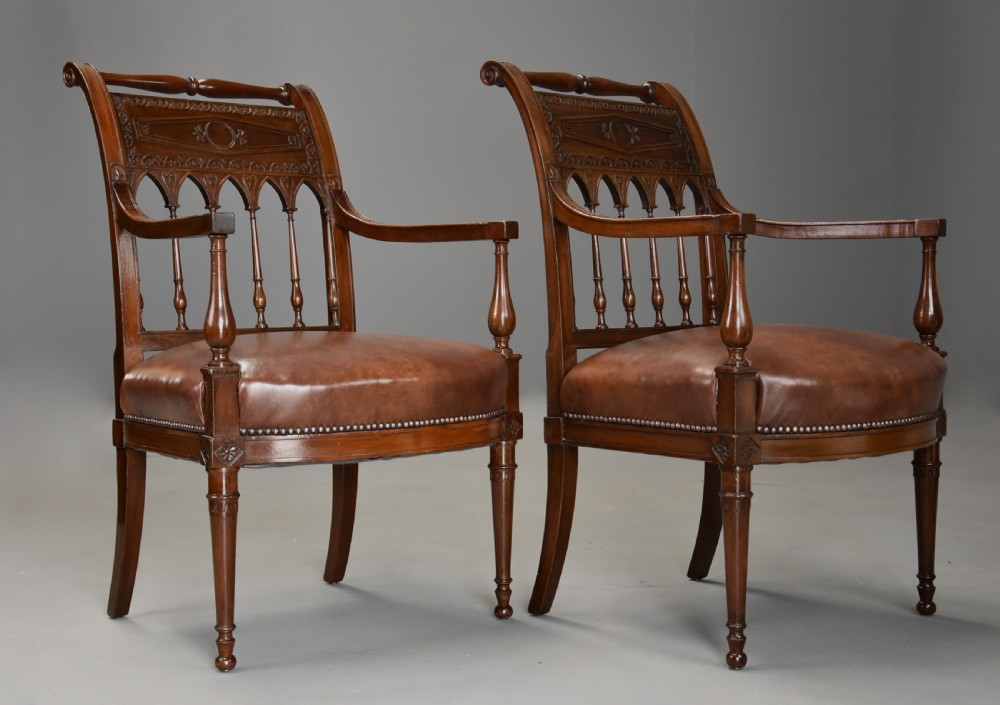 A pair of late 18th-century French Directoire style carved walnut open armchairs with studded brown leather seats. View IV