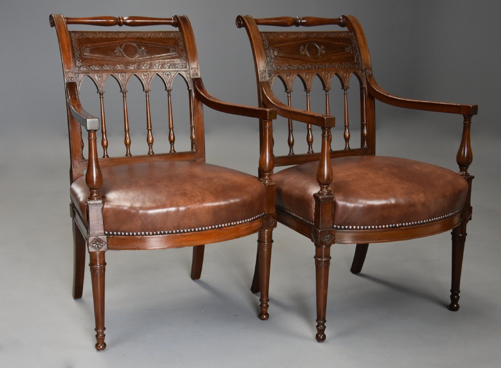 A pair of late 18th-century French Directoire style carved walnut open armchairs with studded brown leather seats. View VI