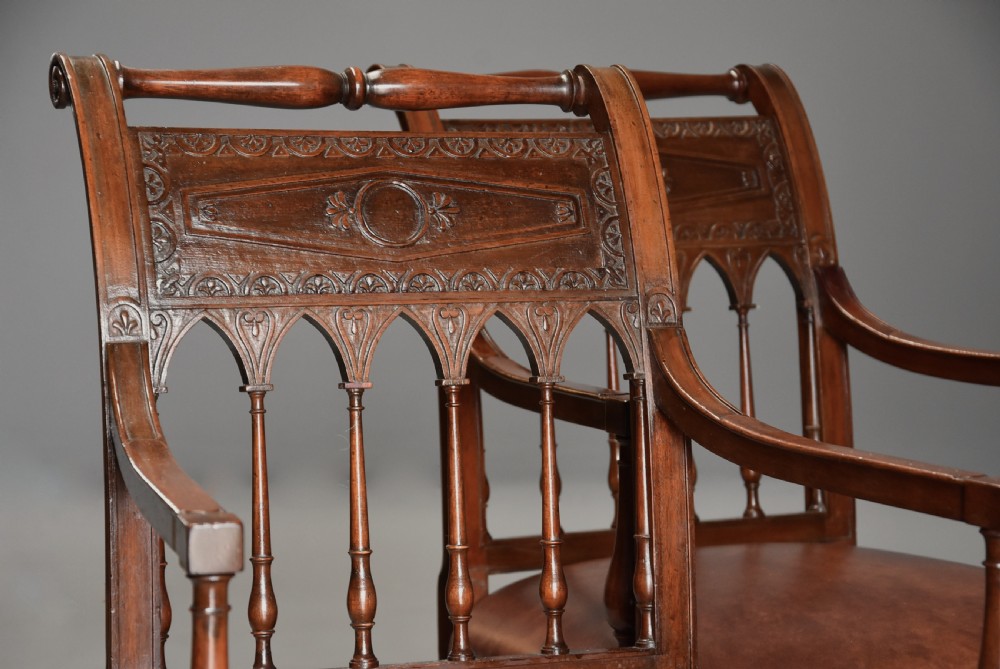A pair of late 18th-century French Directoire style carved walnut open armchairs with studded brown leather seats. View X