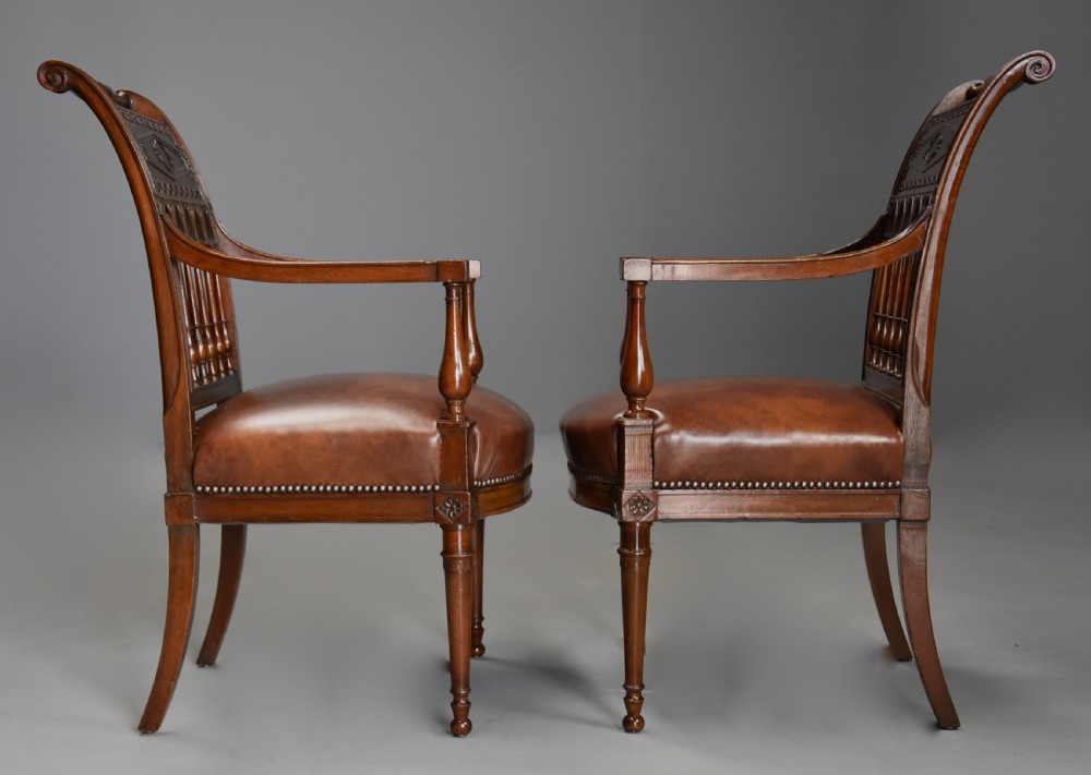 A pair of late 18th-century French Directoire style carved walnut open armchairs with studded brown leather seats. View XIII