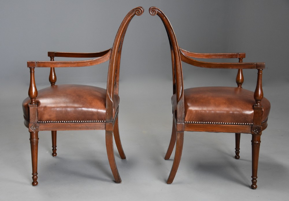 A pair of late 18th-century French Directoire style carved walnut open armchairs with studded brown leather seats. View XIV