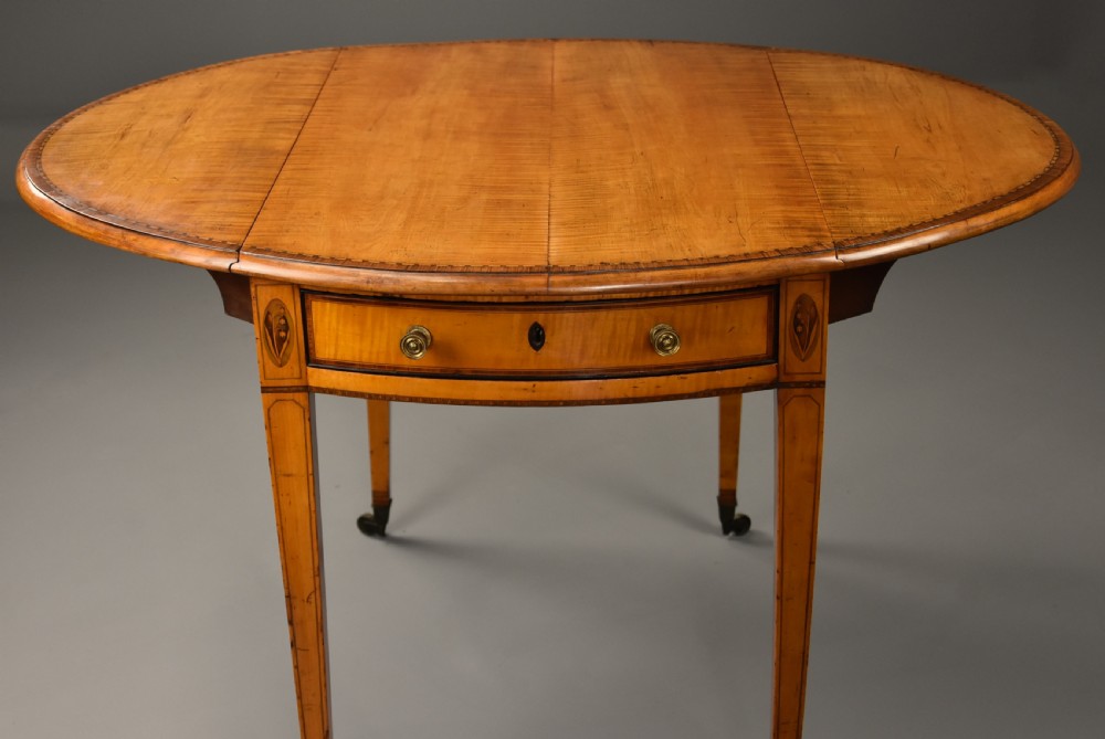 A late 18th-century Georgian Pembroke table made of fiddleback sycamore timber with two drop leaves, a single drawer with brass knobs, and tapered legs on brass castors. View IV