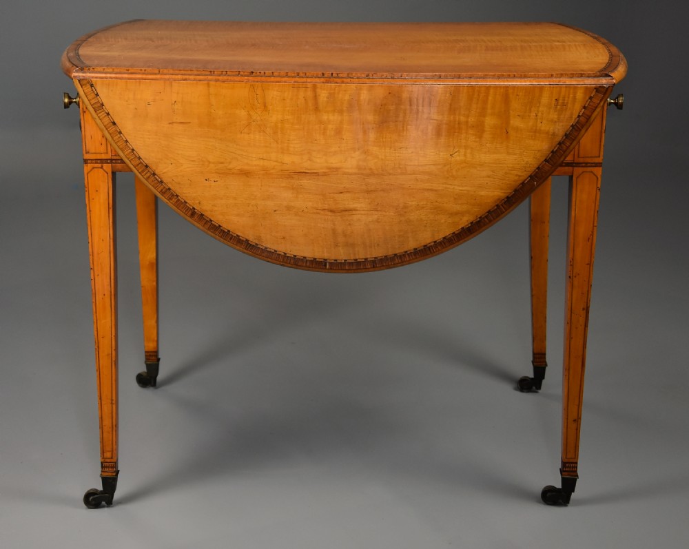 A late 18th-century Georgian Pembroke table made of fiddleback sycamore timber with two drop leaves, a single drawer with brass knobs, and tapered legs on brass castors. View VII