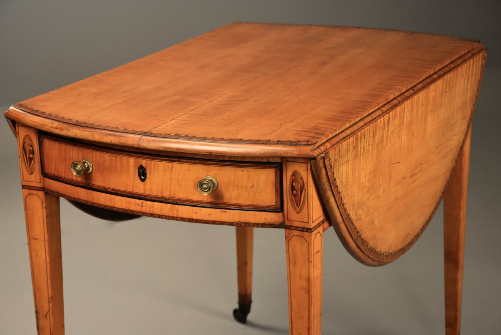 A late 18th-century Georgian Pembroke table made of fiddleback sycamore timber with two drop leaves, a single drawer with brass knobs, and tapered legs on brass castors. View XI