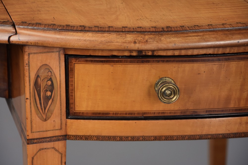 A late 18th-century Georgian Pembroke table made of fiddleback sycamore timber with two drop leaves, a single drawer with brass knobs, and tapered legs on brass castors. View XIII