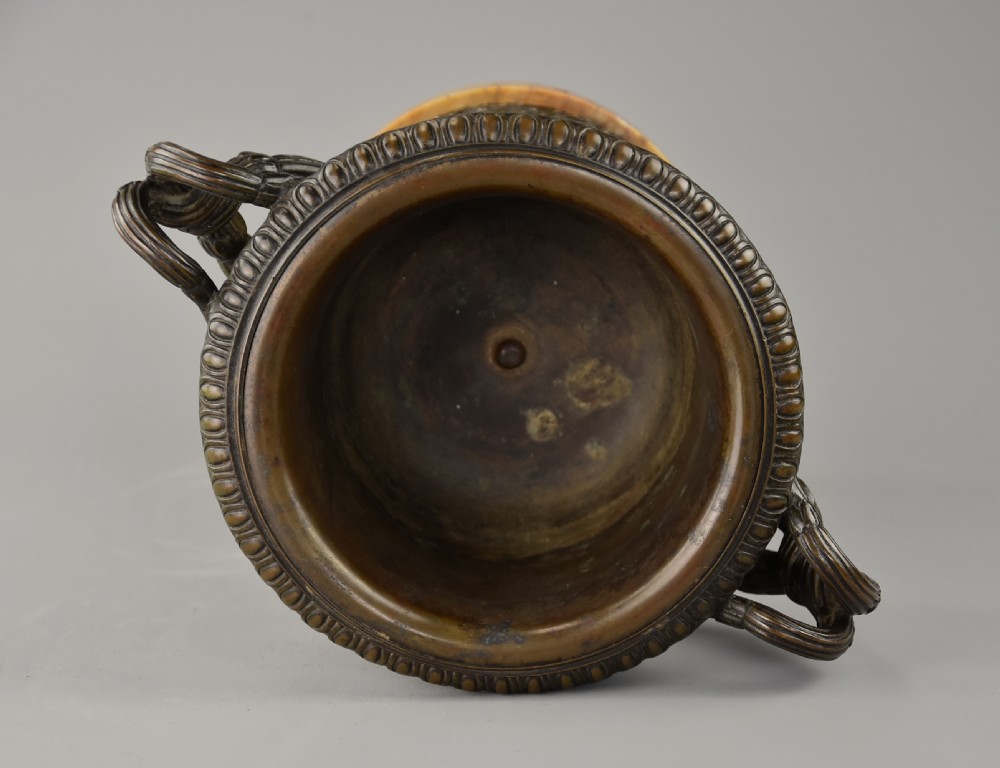 A late nineteenth-century patinated bronze reduction of the classical Warwick Vase featuring relief satyr masks and entwined handles, set upon a tiered yellow marble base. View VIII