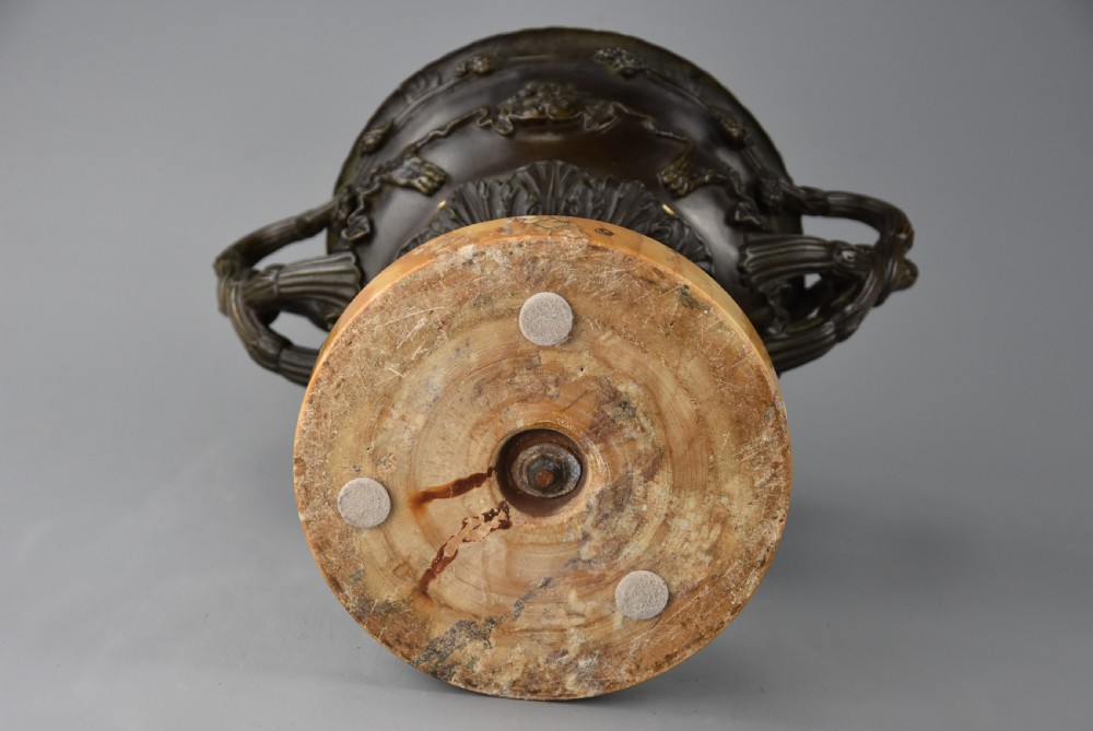 A late nineteenth-century patinated bronze reduction of the classical Warwick Vase featuring relief satyr masks and entwined handles, set upon a tiered yellow marble base. View X