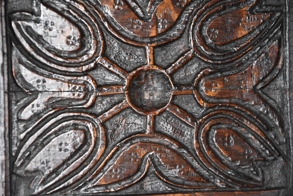 A 17th-century dark oak press cupboard featuring upper carved panel doors, overhanging canopy with pendant drops, and lower paneled double doors. View IX